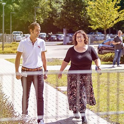 Zwei Personen gehen entlang eines Weges in der Nähe eines Zauns.