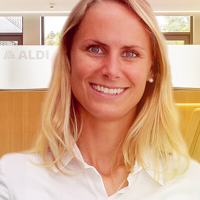 Eine lächelnde Frau mit blonden Haaren und einem weißen Hemd.