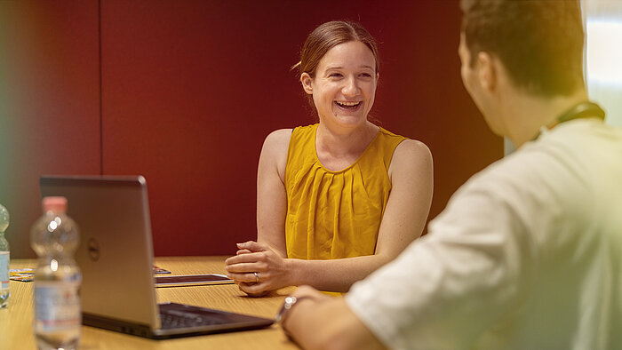 A man and a woman sitting at a table with a laptop.