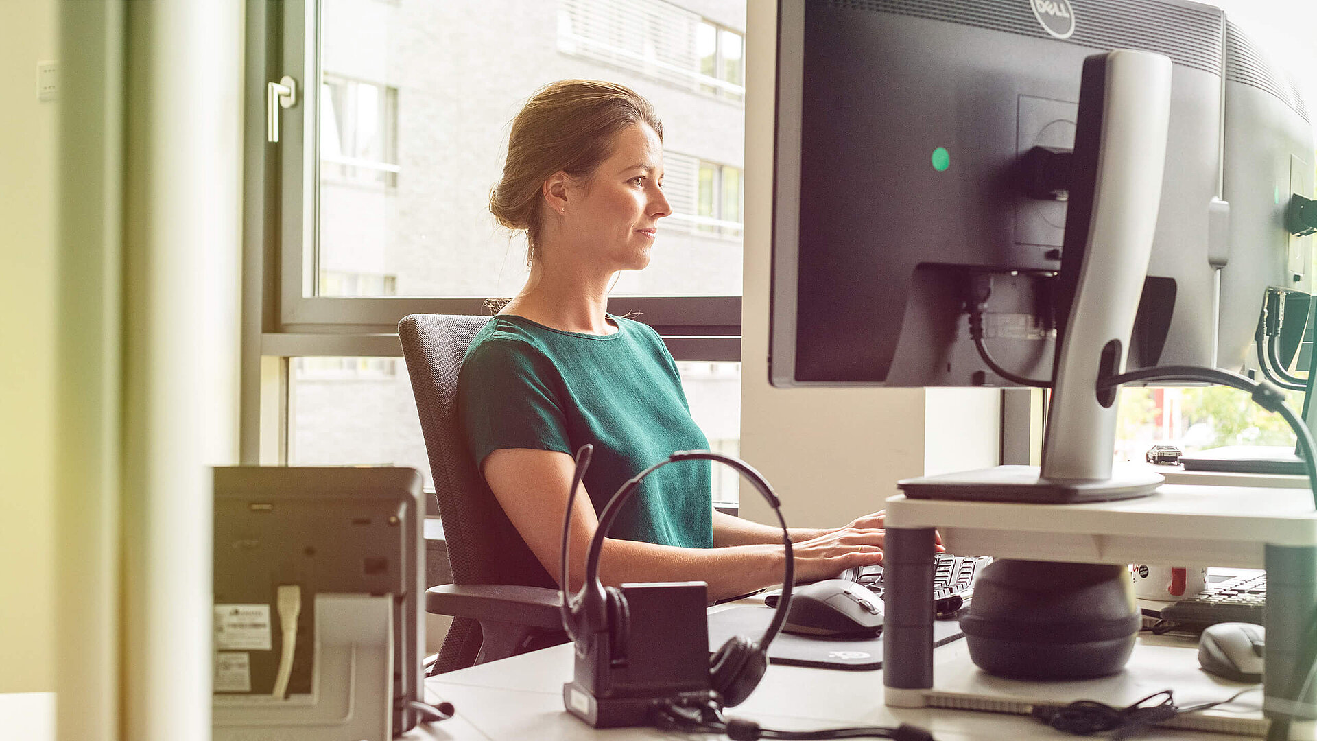 Eine Frau sitzt an einem Schreibtisch mit einem Computer.