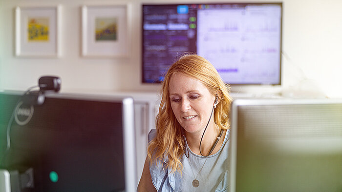 A woman sitting at a desk and wearing headphones.