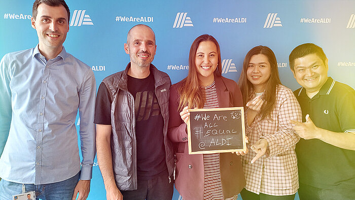 Five people posing for a photo with a sign that reads “We are all equal”.