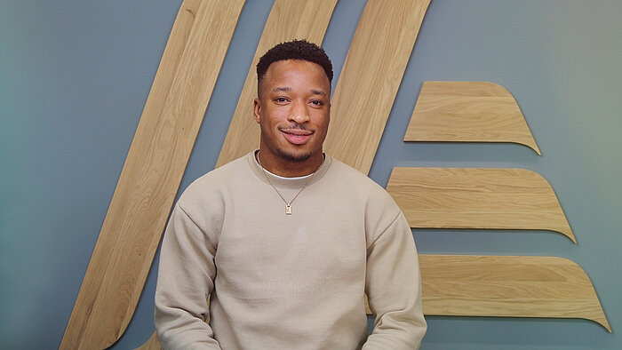 A man in a jumper sitting in front of a wall.