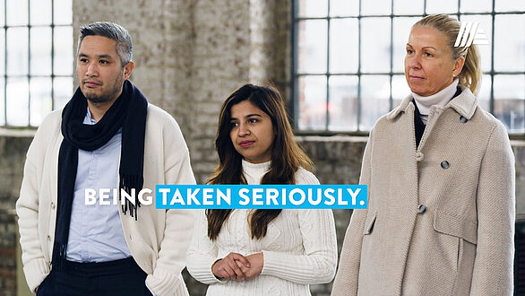 Three people in front of a brick wall – wording “Being Taken Seriously”.