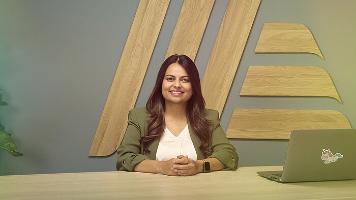 A smiling woman sitting at a table with a laptop.