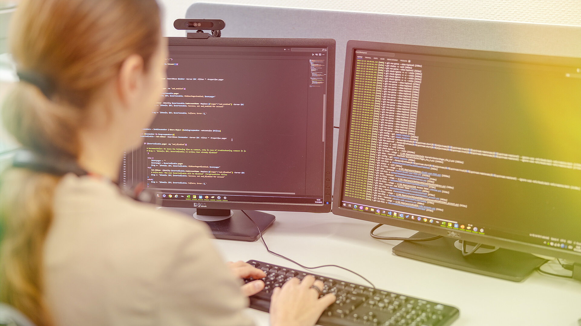 Eine Frau arbeitet an zwei Computerbildschirmen.