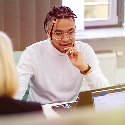 Ein Mann mit Laptop sitzt an einem Schreibtisch