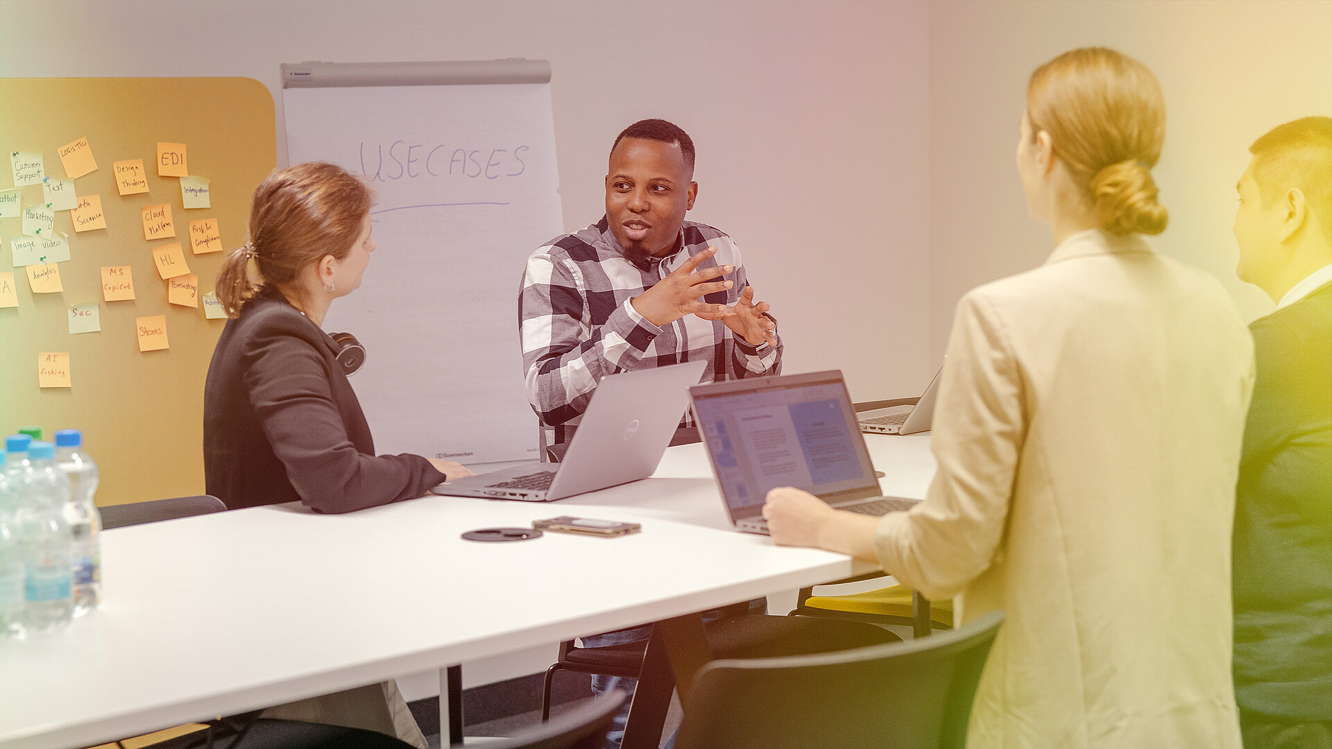 A group of people standing around a table and working with laptops.