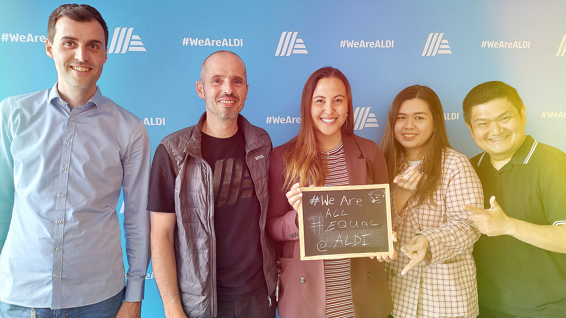 A group of people posing for a photo with a sign that reads “We are all Equal”.