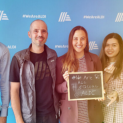 Eine Gruppe von Menschen posiert für ein Foto mit einem Schild "We are all Equal"