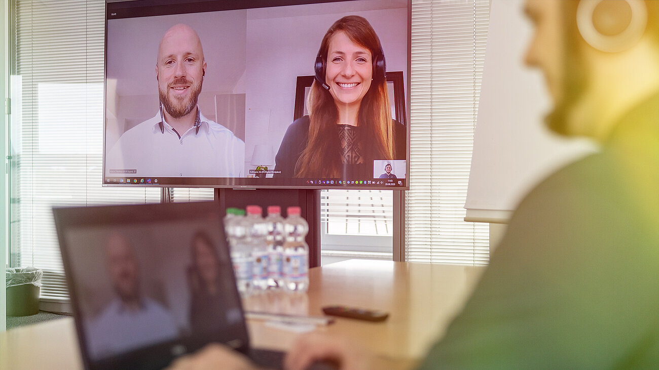 A man and a woman in a video call. They are smiling and talking via the screen.