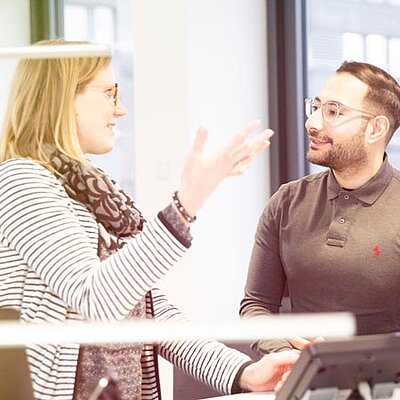 Zwei Personen haben ein Gespräch in einem Büro.