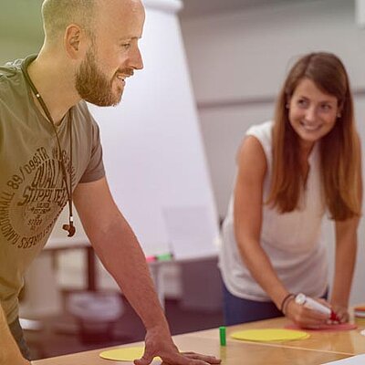 Ein Mann und eine Frau stehen um einen Tisch mit Papier herum.