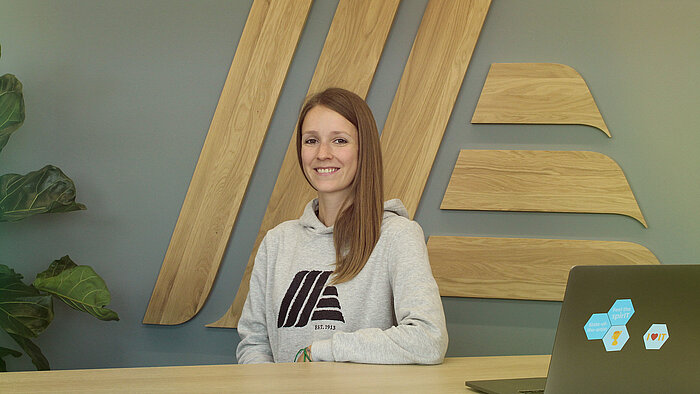 A smiling woman sitting at a desk with a laptop.