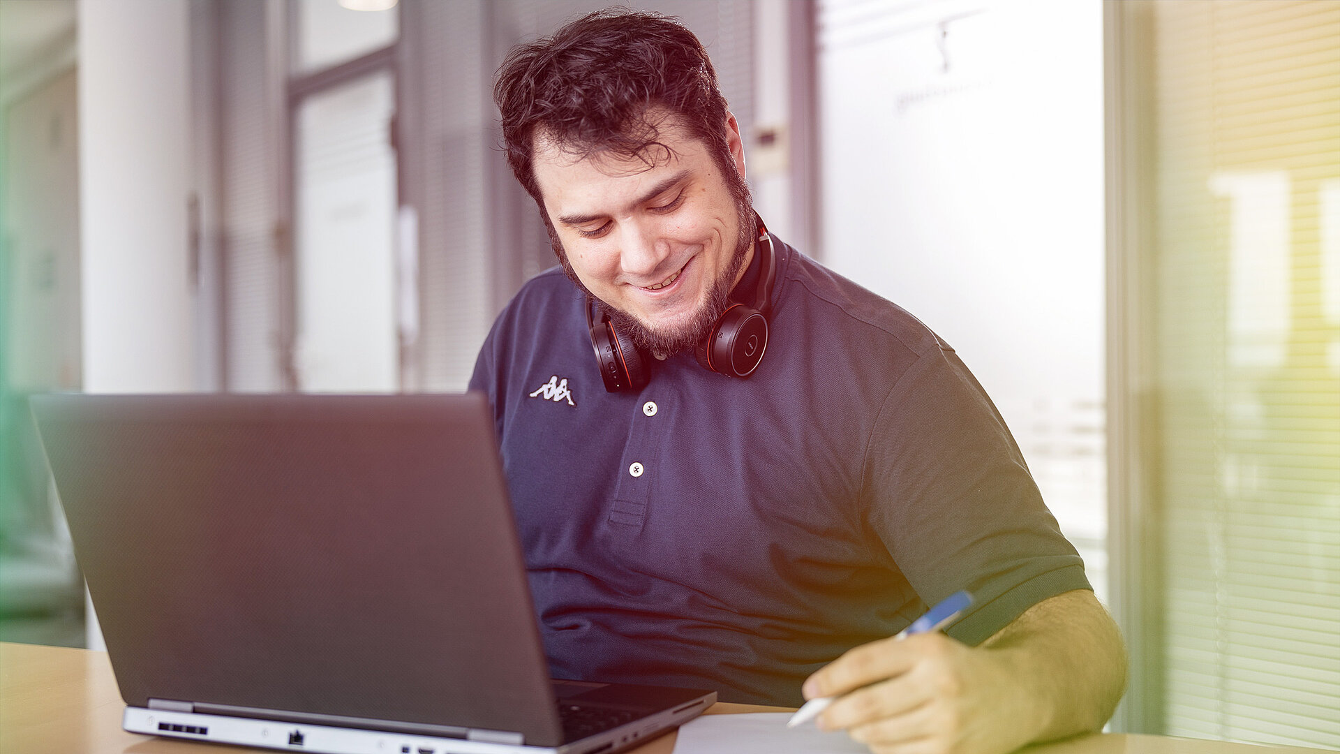 Ein Mann mit Kopfhörern arbeitet an seinem Laptop.