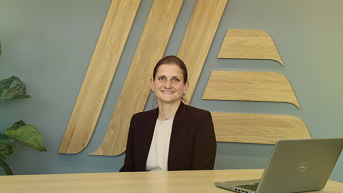 A smiling woman sitting at a desk with a laptop.