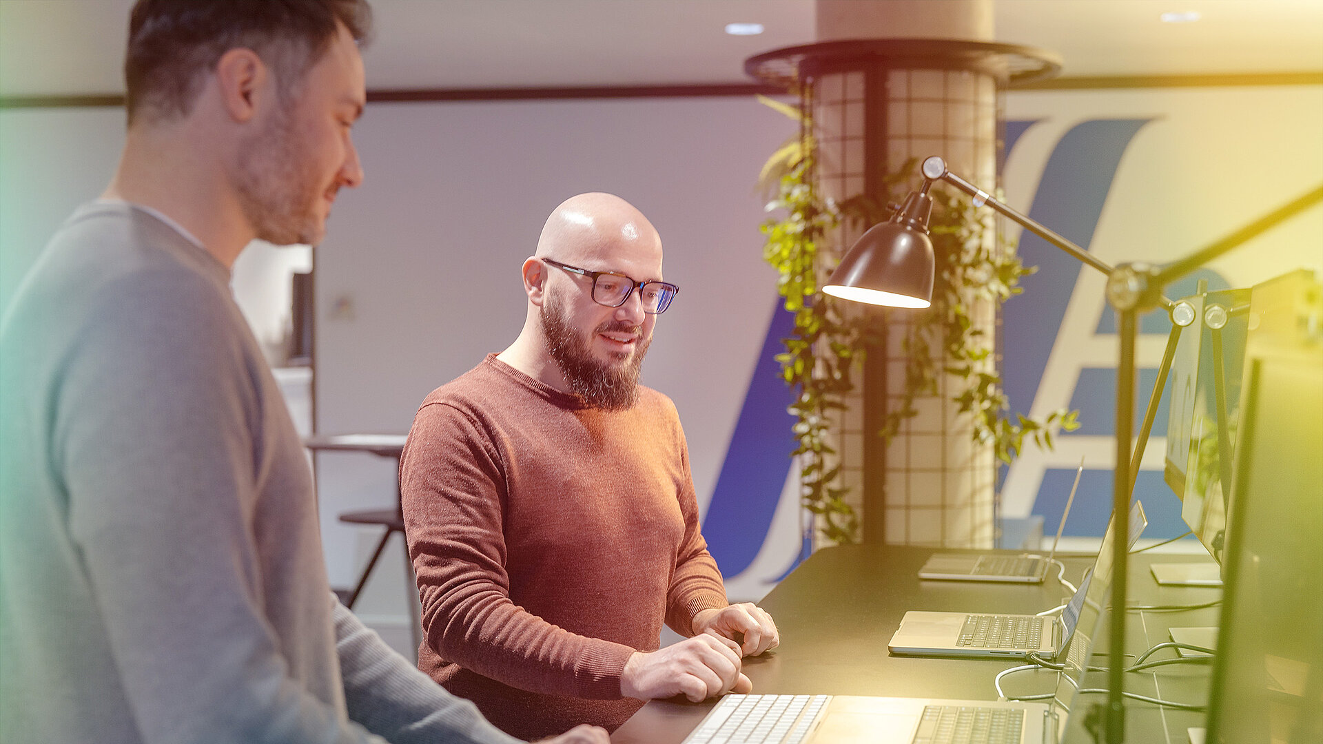 Zwei Männer arbeiten in einem Büro an Computern.