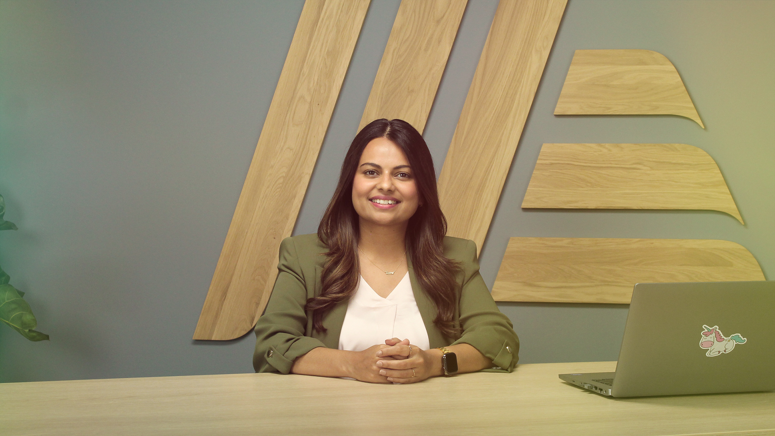 A smiling woman sitting at a table with a laptop.