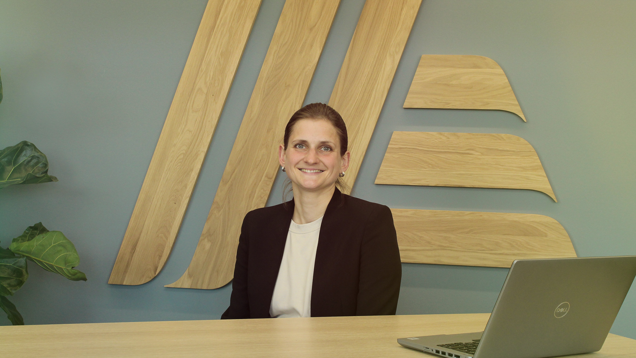 A smiling woman sitting at a desk with a laptop.