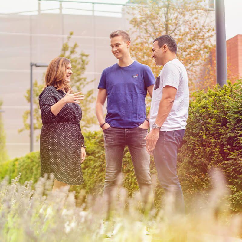 Three people talking in front of a building.