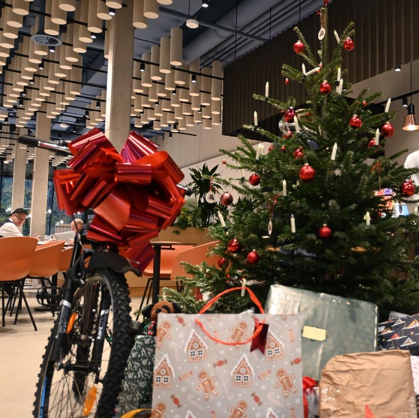 A bicycle and Christmas presents in a restaurant, festively decorated for the holidays.