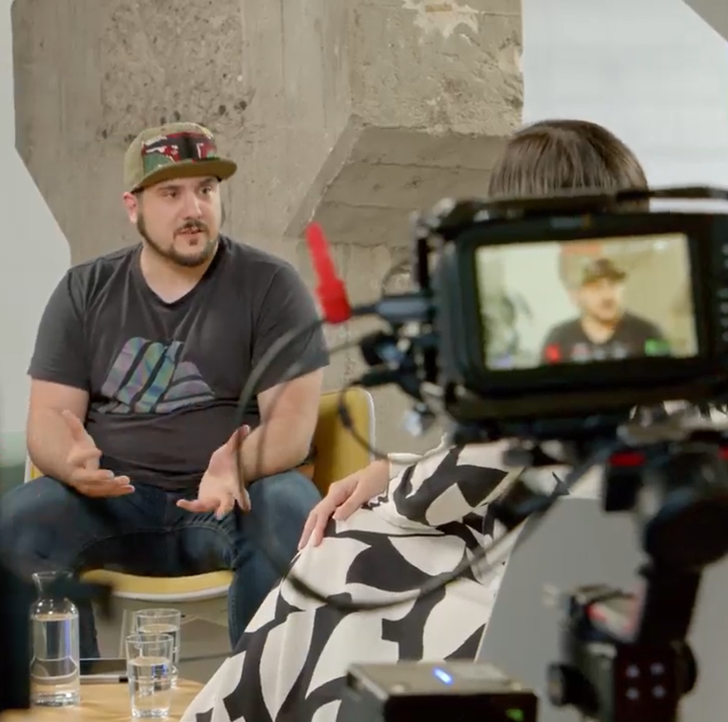A man sitting in front of a camera and a woman sitting next to him.