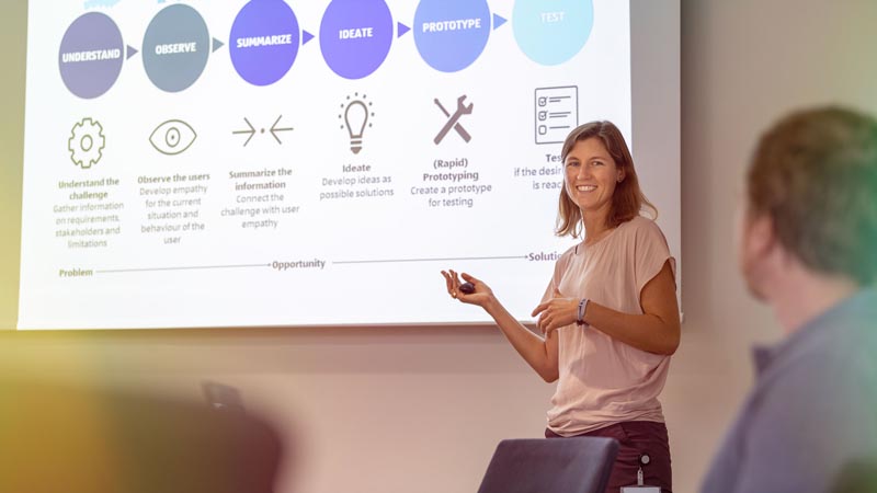 A woman giving a presentation to an audience at a conference.