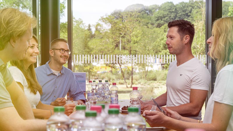 A group of people sitting around a table with bottles of water on it.