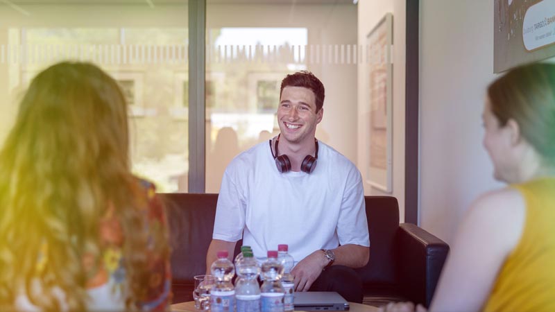 Three people with headphones talking at a table.